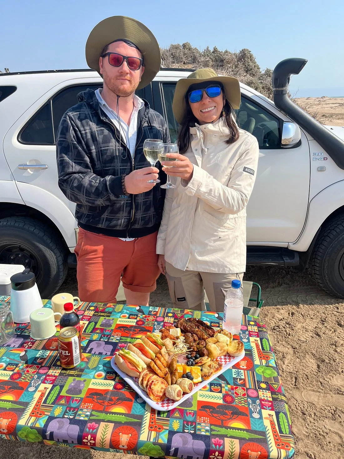 Two guests beside a picnic table and tour vehicle