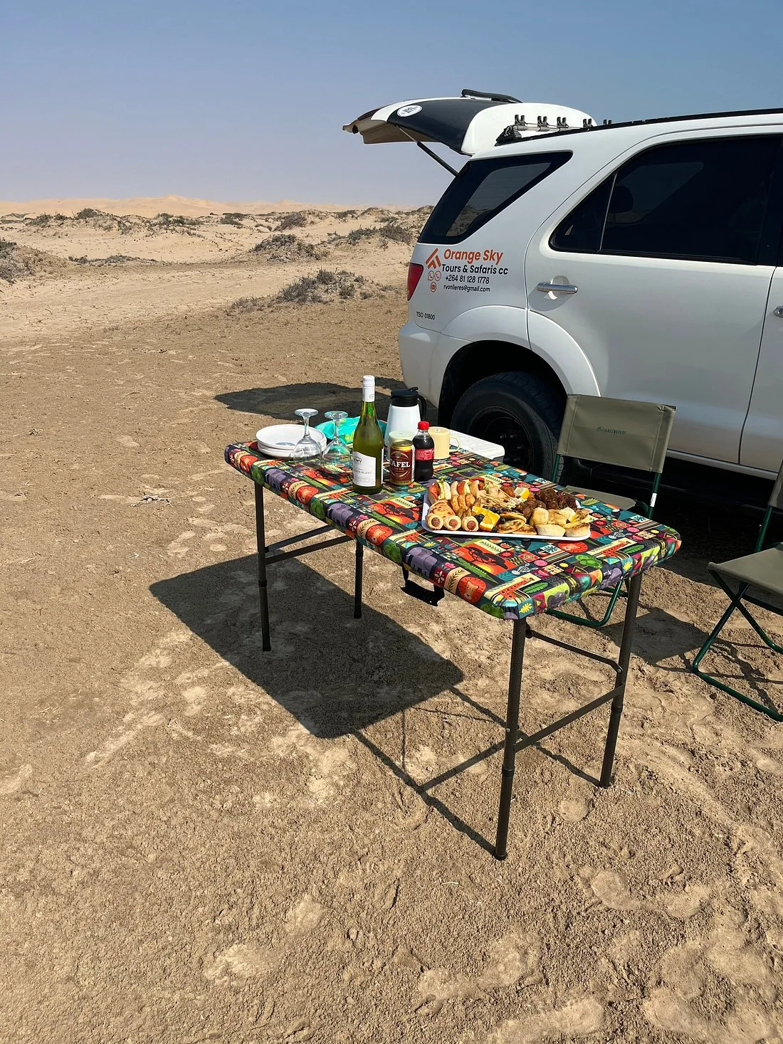 A picnic table set beside an Orange Sky vehicle in the desert